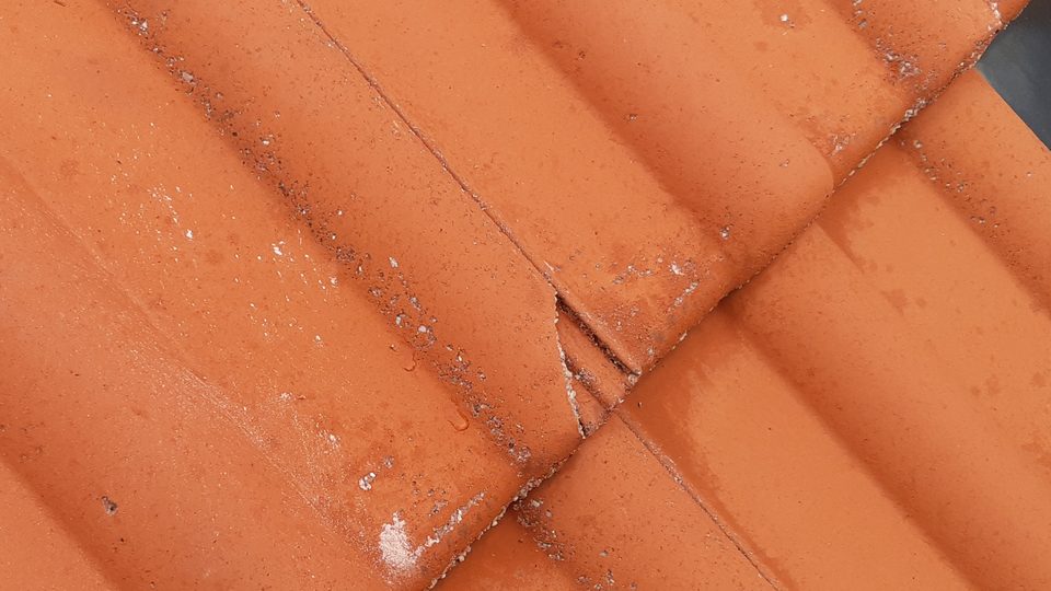 Nahaufnahme roter Dachziegel mit einem gerissenen Ziegel Nahaufnahme roter Dachziegel mit einem gerissenen Ziegel