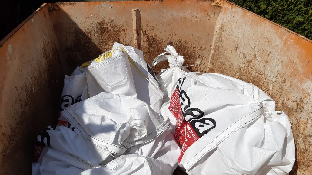Absetzcontainer mit befüllten weißen Big Bags, bedruckt mit rotem Asbest-Warnhinweis Absetzcontainer mit befüllten weißen Big Bags, bedruckt mit rotem Asbest-Warnhinweis